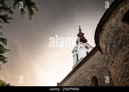 Bild des ikonischen Uhrturms der serbischen orthodoxen Kirche von Stari Slankamen, in Serbien, aufgenommen während eines warmen Sonnenuntergangs. Stari Slankamen auch bekannt Stockfoto