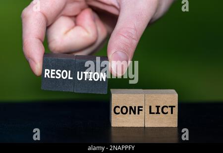 Wählt Holzwürfel mit der Hand mit dem Ausdruck „Auflösung“ statt Würfel mit dem Wort „Konflikt“ aus. Symbol zum Lösen eines Konflikts. Stockfoto