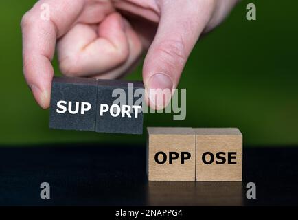 Mit der Hand werden Holzwürfel mit dem Wort Stütze anstelle von Würfeln mit dem Wort Oppose ausgewählt. Stockfoto
