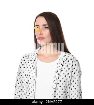 Junge Frau mit Wäschespin auf weißem Hintergrund. Das Runny-Nose-Konzept Stockfoto