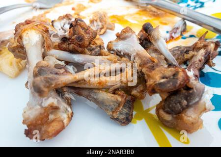 Hühnerflügelknochen, die am Ende einer Mahlzeit auf einem Teller zurückgeblieben sind. Stockfoto