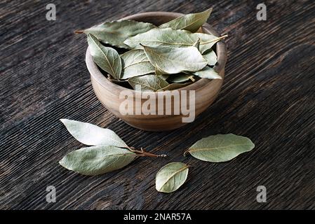 Getrocknete Lorbeerblätter in Schüssel auf Holztischhintergrund. Aromatische Blätter zum Kochen Stockfoto