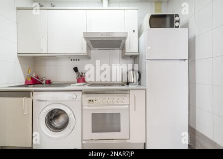 Kleine Küche mit weißen Schränken in einer Ferienwohnung Stockfoto