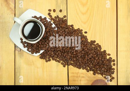 tasse mit Kaffee auf einem Holztisch mit Kaffeebohnen Stockfoto