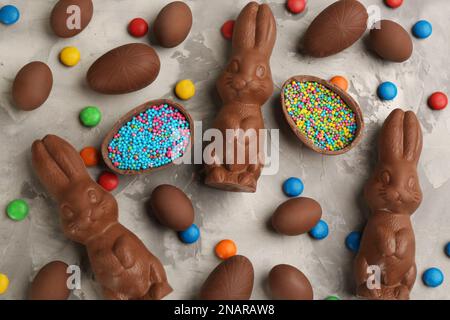 Flache Laienzusammensetzung mit Schokoladen-Osterhasen, Eiern und Süßigkeiten auf hellgrauem Tisch Stockfoto