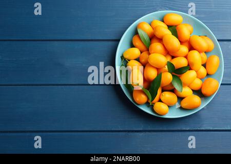 Frische reife Kumquats auf blauem Holztisch, Blick von oben. Platz für Text Stockfoto