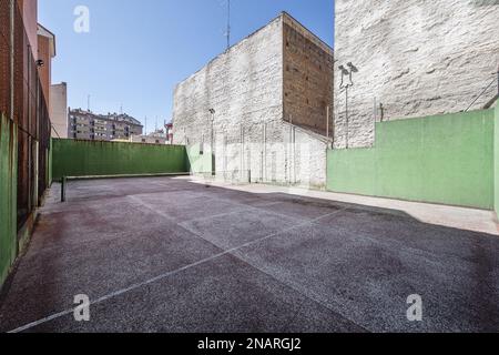 Ein städtischer Tennisplatz in einem Blockhof zwischen Gebäuden mit hohen Betonwänden Stockfoto