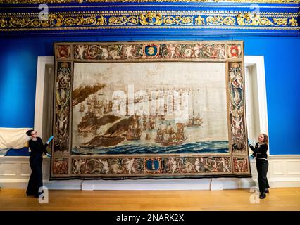 (Von links nach rechts) die Kuratoren Allison Goudie und Imogen Tedbury vom Queen's House passen den Solebay-Wandteppich an, nachdem er in der Anwesenheitskammer des Königs im Queen's House in Greenwich, Süd-London installiert wurde. Der Wandteppich ist das Hauptobjekt der bevorstehenden Ausstellung, The Van de Veldes: Greenwich, Art and the Sea. Foto: Montag, 13. Februar 2023. Stockfoto