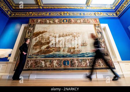 (Von links nach rechts) die Kuratoren Allison Goudie und Imogen Tedbury vom Queen's House beobachten den Solebay Tapestry, nachdem er in der Anwesenheitskammer des Königs im Queen's House in Greenwich, Süd-London, installiert wurde. Der Wandteppich ist das Hauptobjekt der bevorstehenden Ausstellung, The Van de Veldes: Greenwich, Art and the Sea. Foto: Montag, 13. Februar 2023. Stockfoto