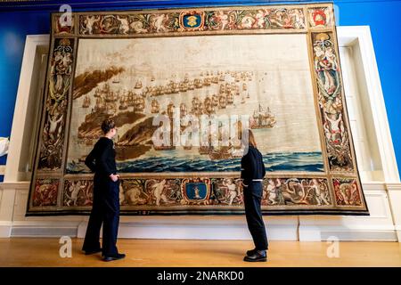 (Von links nach rechts) die Kuratoren Allison Goudie und Imogen Tedbury vom Queen's House beobachten den Solebay Tapestry, nachdem er in der Anwesenheitskammer des Königs im Queen's House in Greenwich, Süd-London, installiert wurde. Der Wandteppich ist das Hauptobjekt der bevorstehenden Ausstellung, The Van de Veldes: Greenwich, Art and the Sea. Foto: Montag, 13. Februar 2023. Stockfoto