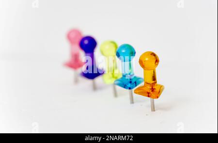Viele farbenfrohe Stecknadeln auf weißem Farbkonzept. Stockfoto