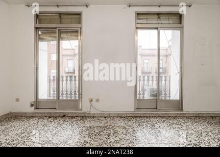 Wohnzimmer in einem alten Haus mit Terrazzo-Böden aus dem 70s. Jahrhundert und ein paar Balkonen mit Glas- und Aluminiumtüren Stockfoto