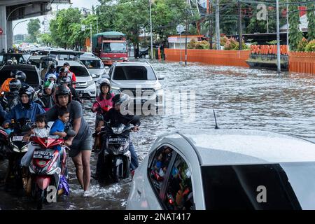 Makassar, Indonesien. 13. Februar 2023. Der Verkehr durchquert ein überflutetes Gebiet nach starkem Regen in Makassar, South Sulawesi, Indonesien, 13. Februar 2023. Kredit: Niaz Sharief/Xinhua/Alamy Live News Stockfoto