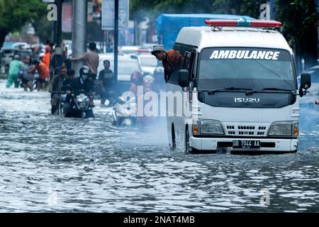 Makassar, Indonesien. 13. Februar 2023. Ein Krankenwagen fährt nach starkem Regen am 13. Februar 2023 in Makassar, South Sulawesi, Indonesien, auf einer überfluteten Straße. Kredit: Niaz Sharief/Xinhua/Alamy Live News Stockfoto