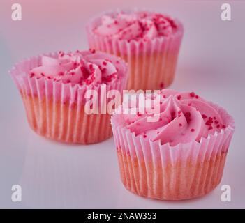 Drei isolierte Cupcakes auf einfachem Hintergrund. Stockfoto