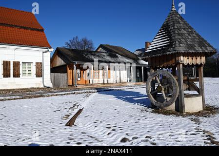 Alte Geschäfte und historische Brunnen auf dem Marktplatz in der polnischen Provinzstadt, wie im ethnologischen Museum in Lublin, Polen, zu sehen - verschneite Winterszene. Stockfoto