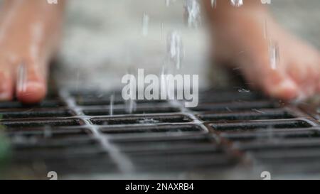 Wasser fließt in das Abwassersystem. Tröpfchen aus öffentlichen Wasserhähnen fallen in Zeitlupe Stockfoto