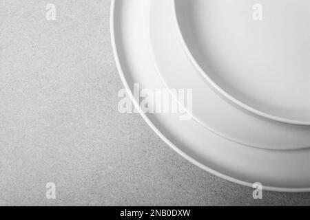 Stapel weißer Porzellanplatten und -Schüsseln auf neutralgrauem Hintergrund. Speicherplatz kopieren Stockfoto