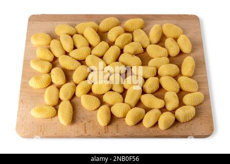 Rohe Gnocchi auf Holzschneidplatte isoliert auf weiß mit Schneideweg. Teigtaschen mit Mehl und gekochten Kartoffeln Stockfoto