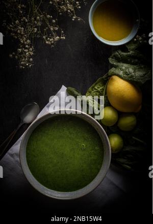 Spinatcreme mit Zitronen, Olivenöl und Spinatblättern. Fotografiert in dunkler Stimmung Ästhetik Stockfoto