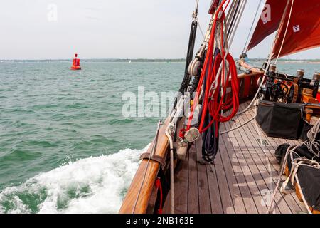 An Bord des traditionellen Spafenschneiders „Jolie Brise“, während sie über Solent, Hampshire, Großbritannien reicht und eine feine Bogenwelle erzeugt Stockfoto