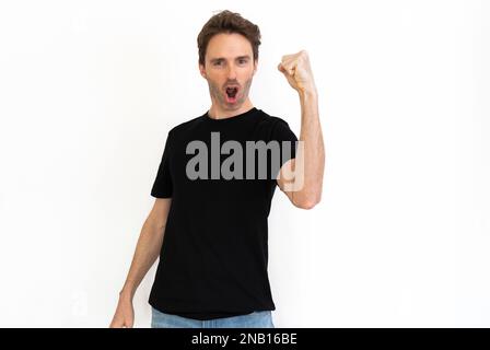 Hübsches männliches Model posiert in einem schwarzen T-Shirt, jubelt und sieht glücklich aus. Schwarzes Modell. Stockfoto