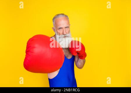 Foto einer fokussierten Person Tragen Sie Boxhandschuhe Stanzung isoliert auf gelbem Hintergrund Stockfoto