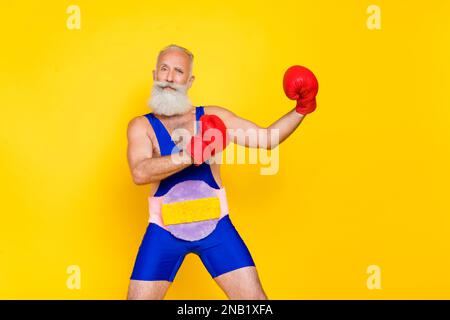 Foto eines attraktiven, charismatischen Großvaters. Boxhandschuhe, die isoliert auf gelbem Hintergrund kämpfen Stockfoto