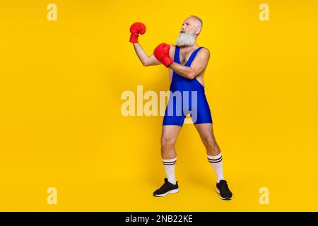 Großes Foto eines ernsthaften, konzentrierten Sportlers, der einen leeren Raum auf gelbem Hintergrund kämpft Stockfoto