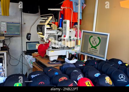 Mehrfarbige sechs-Kopf-Stickerei zwölf Nadeln gewerbliche Stickerei Maschine Logo auf Hut im Touristenzentrum von Maspalomas, Gran Canaria Stockfoto