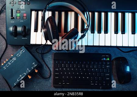 Tastatur oder Synthesizer mit Kopfhörern und Soundkarte. Computeraufnahme und Musikproduktionskonzept. Musik und digitale Studioaufnahmen zu Hause. Stockfoto
