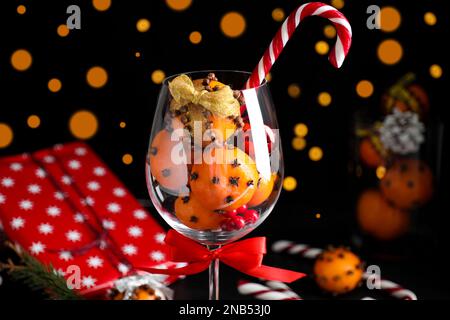 Weihnachtskomposition mit tangerinen Pomanderbällen im Weinglas gegen verschwommenes Licht Stockfoto