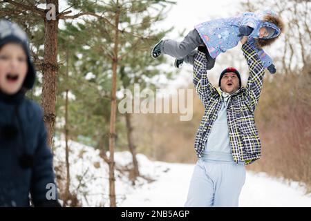 Die Tochter reitet mit ihrem Vater im Winterwald. Stockfoto