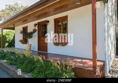 Alte 1877 im französischen Stil erbaute Hausfassade mit weißem Stuck, rötlich braun gebeizte Holzfenster im Sommer. Stockfoto