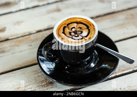 Eine Nahaufnahme einer Blumenzeichnung auf dem Cappuccino-Schaum Stockfoto