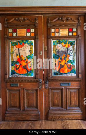 Alte Holztüren mit Buntglasfenstern und geschnitzten Details im Wohnzimmer in einem alten Haus im Landhausstil aus 1826. Stockfoto