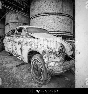 Ein altes, ruiniertes und rostiges fiat-Auto in einer verlassenen Garage Stockfoto