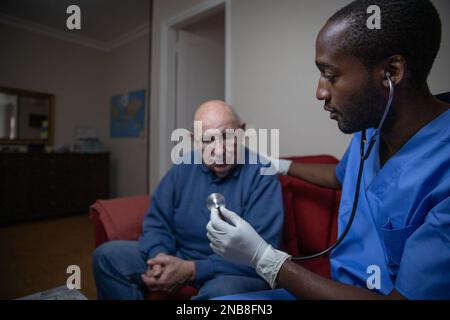 Ein afroamerikanischer Arzt mit Stethoskop besucht einen Patienten zu Hause. Stockfoto