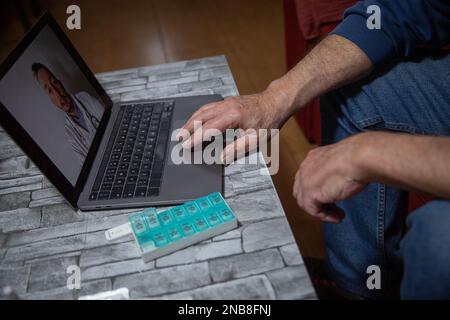 Hand eines älteren Mannes während einer Videokonferenz mit seinem Hausarzt, Telehealth-Konzept. Stockfoto