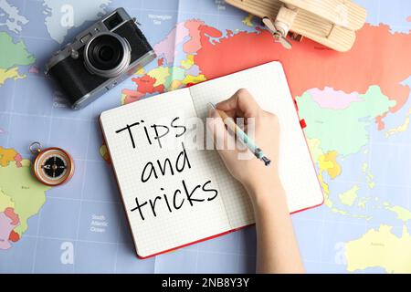 Frau plant Urlaub auf der Weltkarte, Draufsicht. Reisetipps und -Tricks Stockfoto