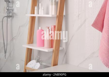 Weiche Handtücher und verschiedene Toilettenartikel auf der dekorativen Leiter im Badezimmer. Innendesign Stockfoto