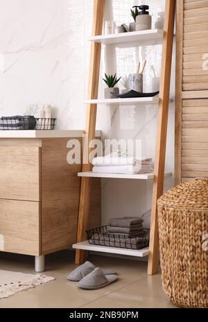 Weiche Handtücher und verschiedene Toilettenartikel auf der dekorativen Leiter im Badezimmer. Innendesign Stockfoto
