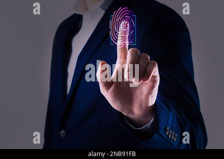 Mann mit biometrischem Fingerabdruck-Scanner auf grauem Hintergrund, Nahaufnahme Stockfoto