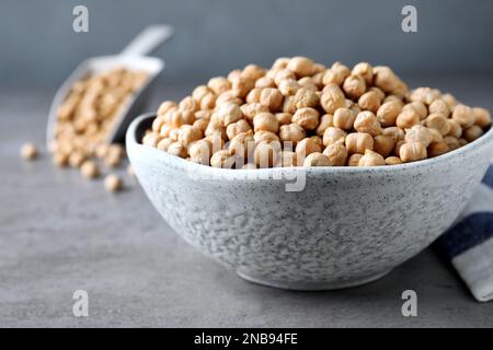 Rohe Kichererbsen in Schüssel auf grauem Tisch, Nahaufnahme Stockfoto