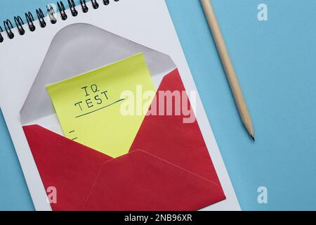 Hinweis mit Text IQ Test im Umschlag, Notizblock und Stift auf hellblauem Hintergrund, flach aufgelegt Stockfoto