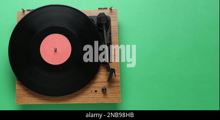 Moderner Plattenspieler mit Vinylplatte auf grünem Hintergrund, Draufsicht Stockfoto