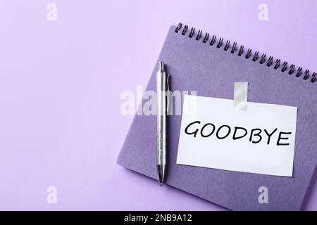 Hinweis mit Wort Auf Wiedersehen, Notizbuch und Stift auf violettem Hintergrund, Platz für Text Stockfoto
