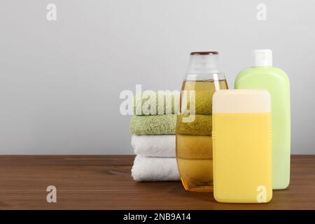 Verschiedene Duschgelflaschen mit Handtüchern auf Holztisch. Platz für Text Stockfoto