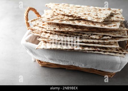 Traditionelle Matzen im Korb auf hellgrauem Tisch, Nahaufnahme Stockfoto