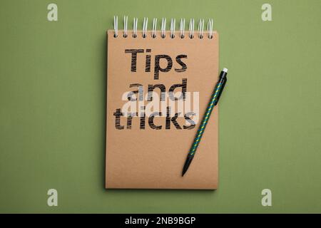 Notizbuch mit Text Tipps und Tricks auf grünem Hintergrund, Draufsicht Stockfoto